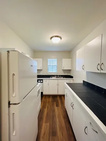 a kitchen with a refrigerator and white cabinets