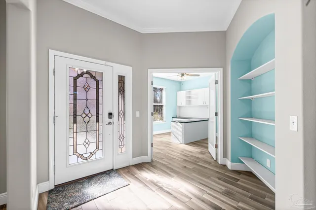 a view of a hallway to a livingroom with wooden floor and kitchen view