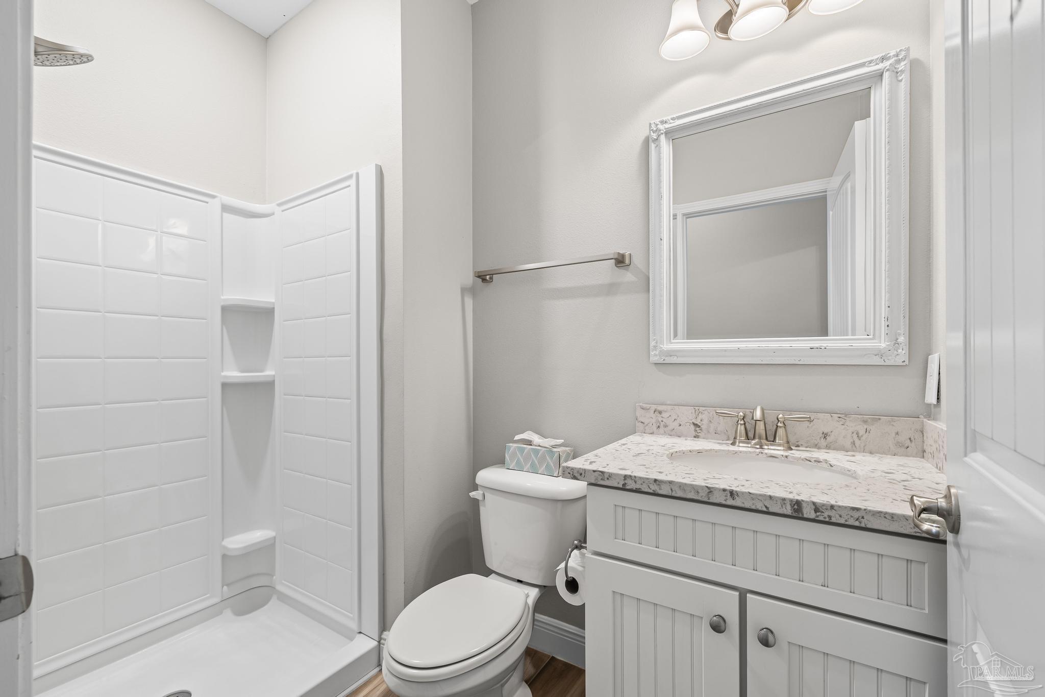 7166 Jasper Street Navarre, FL 32566 - Photo 35 of 71 a bathroom with a granite countertop sink toilet a mirror and shower