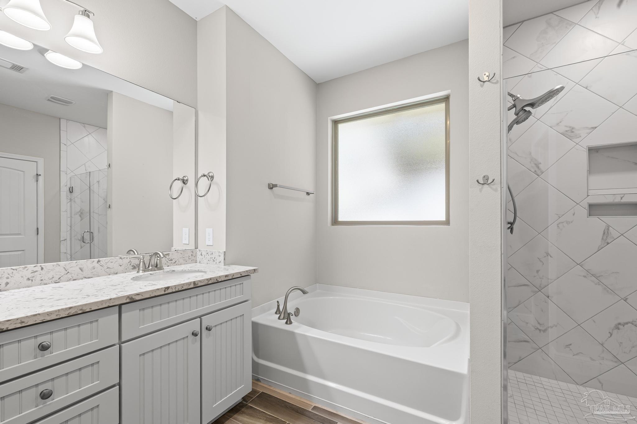 7166 Jasper Street Navarre, FL 32566 - Photo 42 of 71 a bathroom with a tub a sink and mirror