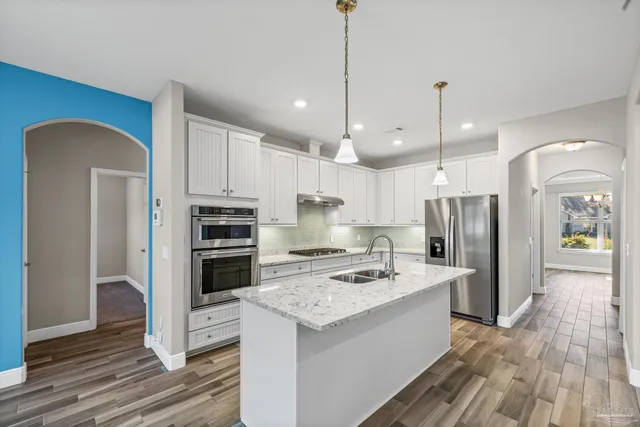 a kitchen with kitchen island granite countertop a stove a sink a center island and cabinets