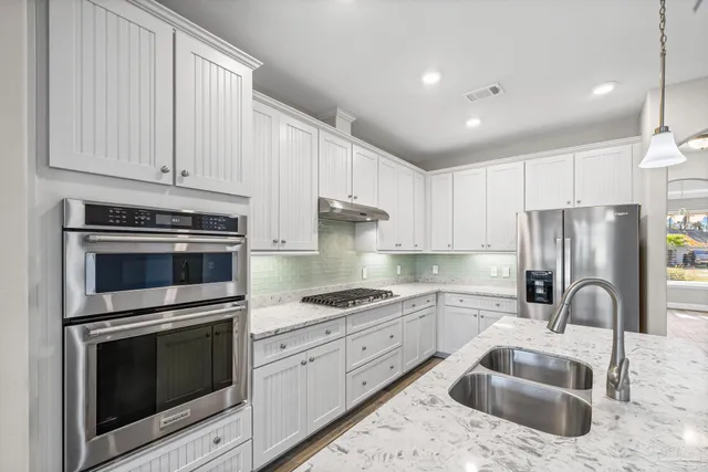 a kitchen with granite countertop white cabinets and stainless steel appliances