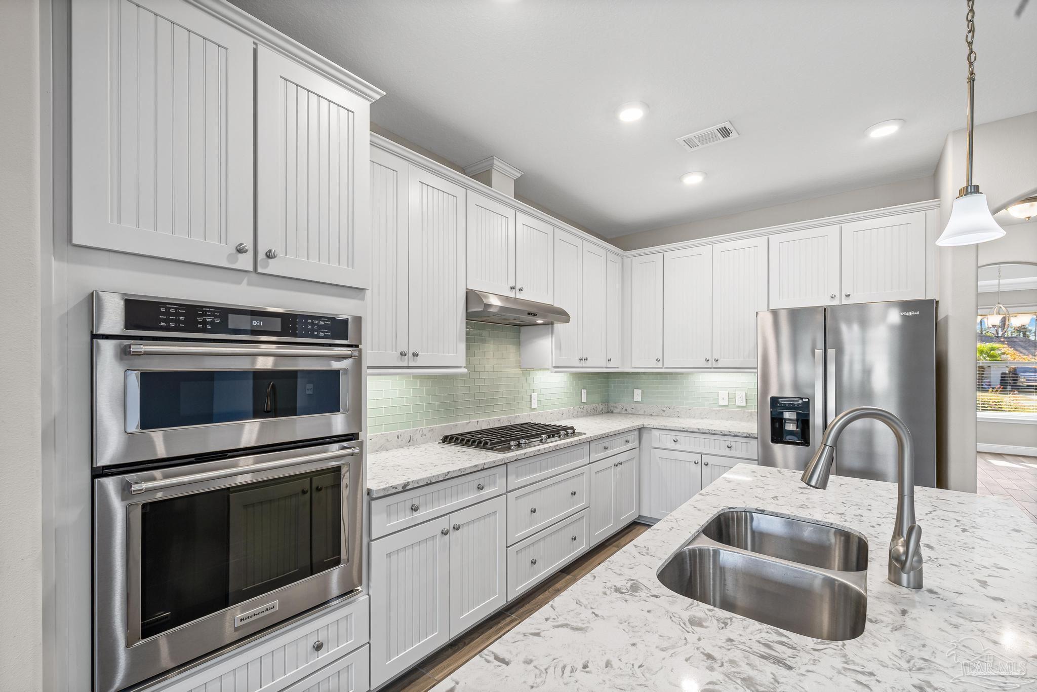 7166 Jasper Street Navarre, FL 32566 - Photo 10 of 71 a kitchen with granite countertop white cabinets and stainless steel appliances