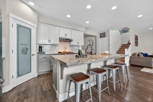 a kitchen with stainless steel appliances kitchen island granite countertop a dining table chairs and wooden floor