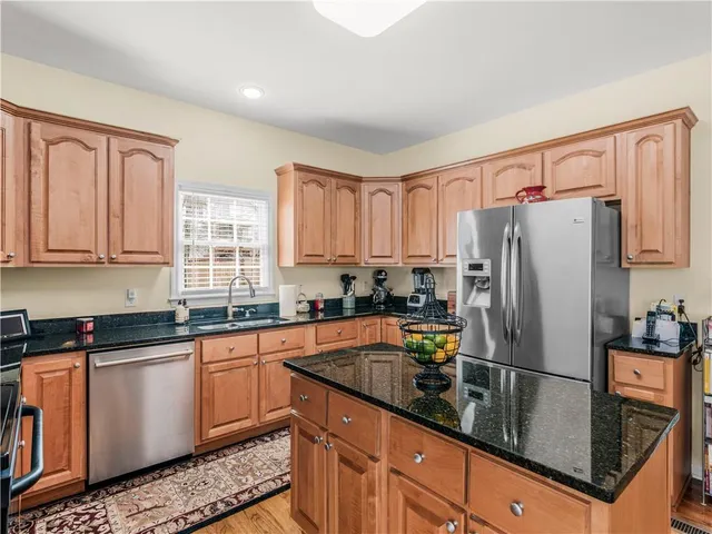 a kitchen with granite countertop a refrigerator sink and cabinets