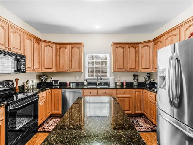 a kitchen with stainless steel appliances granite countertop a stove a sink dishwasher a refrigerator and cabinets with wooden floor