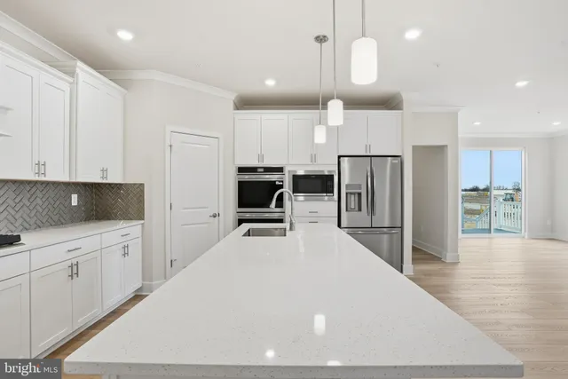 a large white kitchen with a refrigerator a stove and a sink with wooden floor