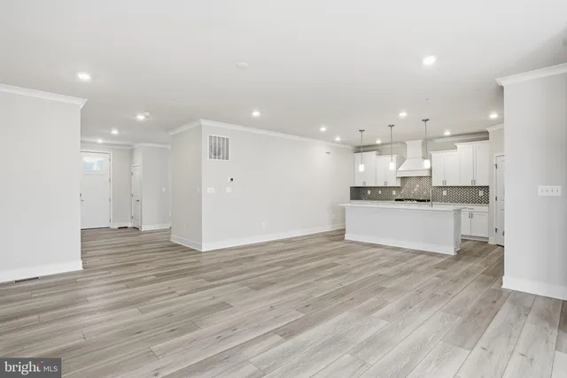 a view of kitchen with kitchen island wooden floor granite counter tops and white cabinets