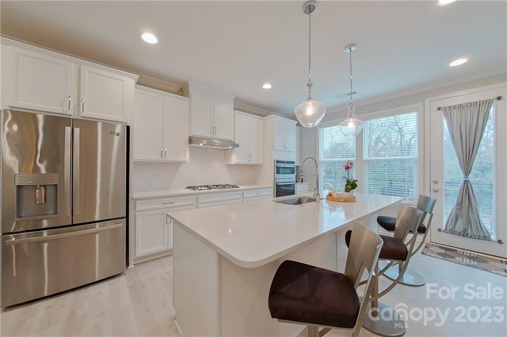 511 Upper Stone Circle Charlotte, NC 28211 - Photo 9 of 32 a kitchen with stainless steel appliances granite countertop a refrigerator a sink dishwasher a stove a dining table and chairs with wooden floor
