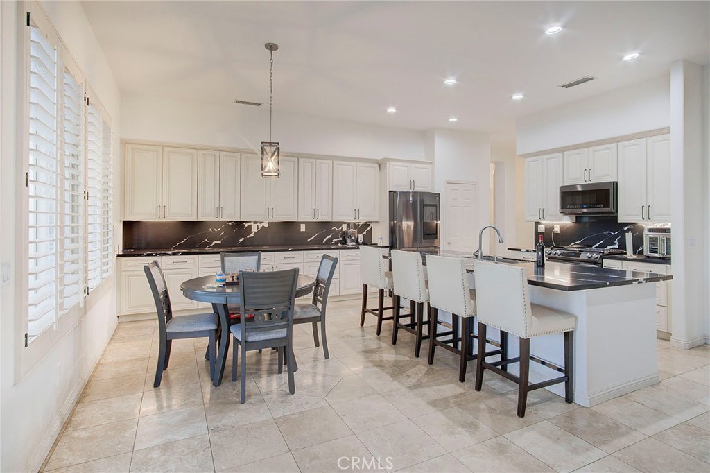 18120 Gentian Avenue Riverside, CA 92508 - Photo 31 of 51 a kitchen with stainless steel appliances kitchen island granite countertop a sink a stove a dining table and chairs