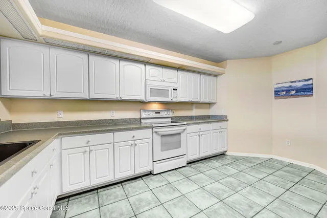 a kitchen with granite countertop white cabinets and white appliances