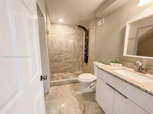 a bathroom with a granite countertop sink toilet and shower
