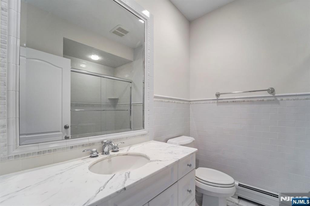 1 Euclid Road Fort Lee, NJ 07024 - Photo 32 of 50 a bathroom with a granite countertop sink toilet a mirror and shower