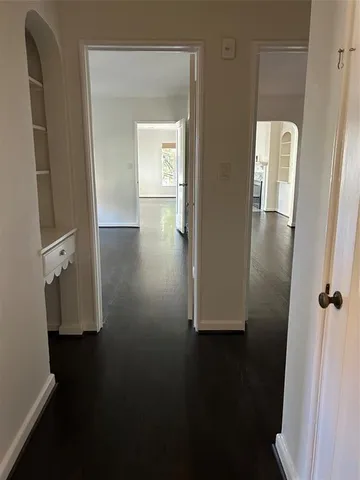 a view of a hallway with wooden floor and a cabinet