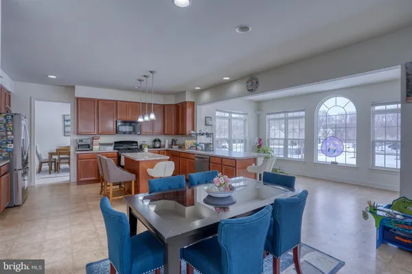 a dining room with stainless steel appliances kitchen island granite countertop a dining table chairs and a refrigerator