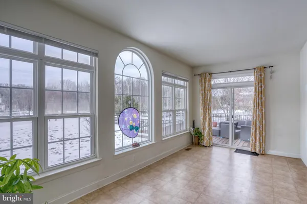 an empty room with windows wooden floor and front door