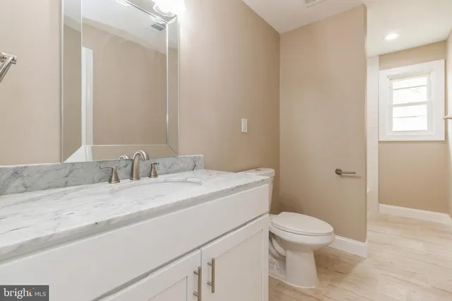 a bathroom with a granite countertop sink mirror vanity and toilet