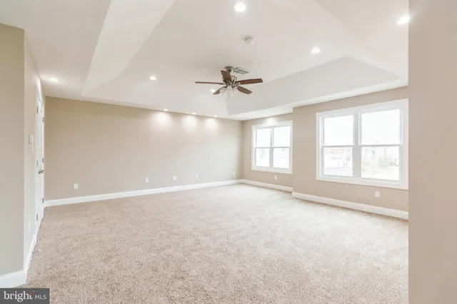 an empty room with windows and chandelier fan