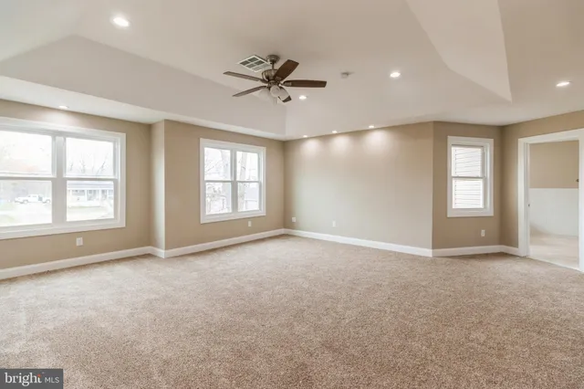 an empty room with windows and ceiling fan