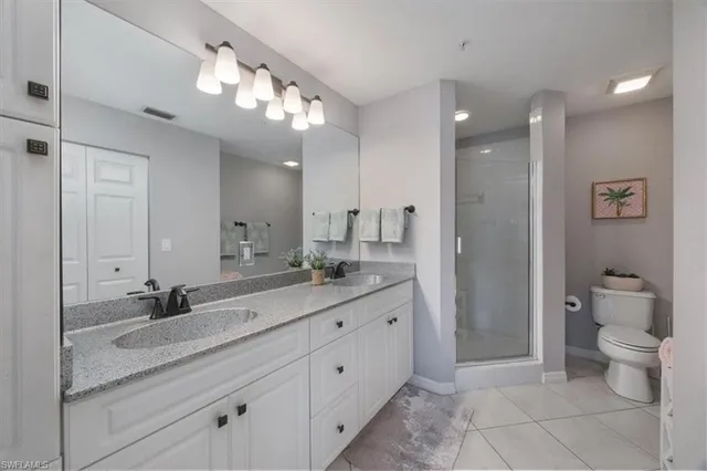 a spacious bathroom with a granite countertop sink a toilet and a mirror