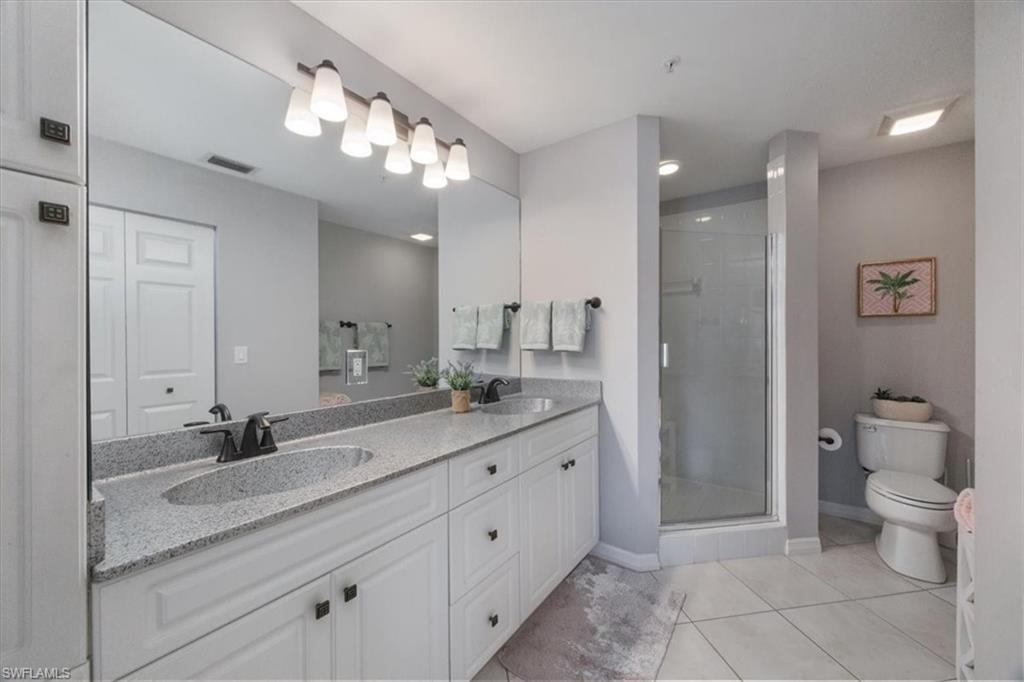 410 Bayfront Place, Unit 2403 Naples, FL 34102 - Photo 9 of 20 a spacious bathroom with a granite countertop sink a toilet and a mirror