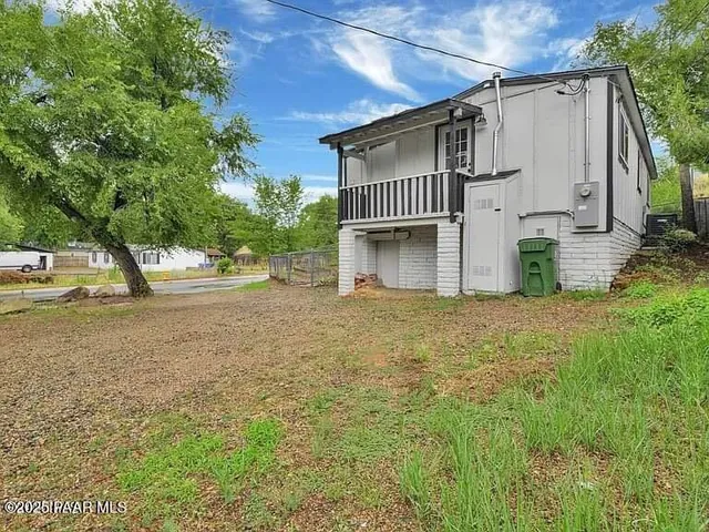 a white house that has tree in front of it