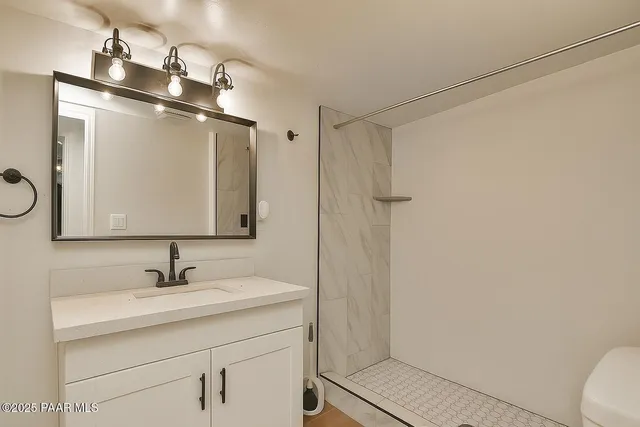 a bathroom with a sink a toilet a mirror and shower