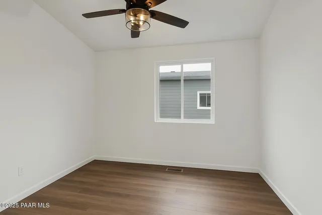 an empty room with wooden floor chandelier fan and windows