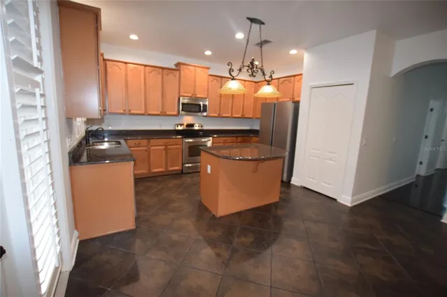 a kitchen with kitchen island granite countertop a refrigerator a sink a stove and white cabinets