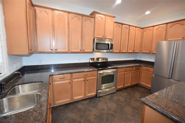 a kitchen with stainless steel appliances granite countertop a refrigerator a sink a stove a microwave and cabinets