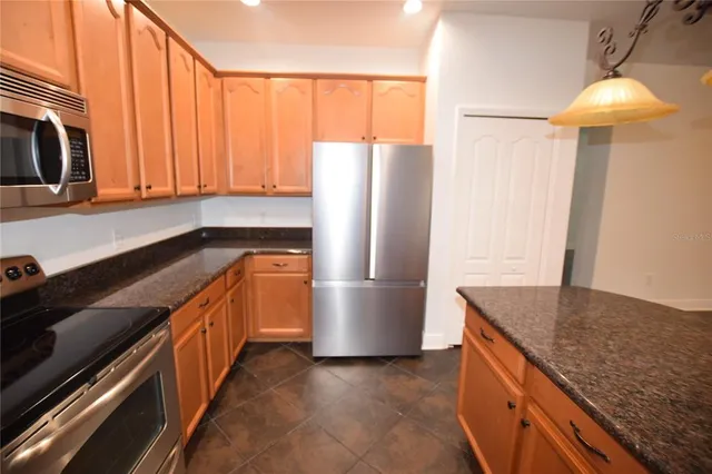 a kitchen with stainless steel appliances granite countertop a refrigerator a sink and a stove
