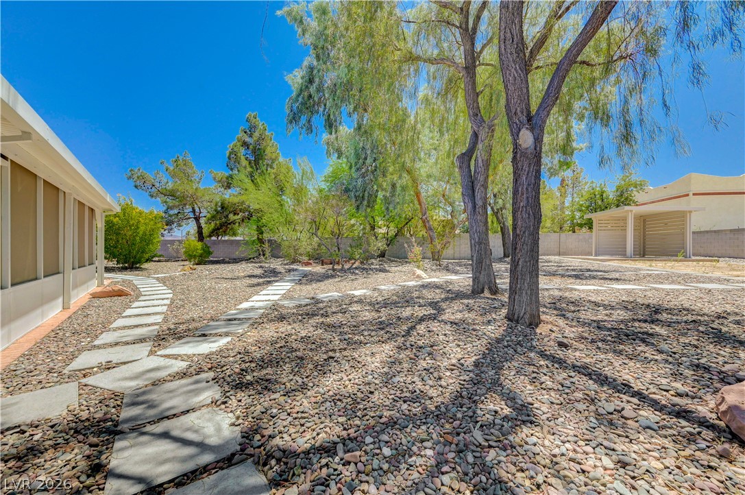 7631 Bermuda Road Las Vegas, NV 89123 - Photo 50 of 64 A meandering stepping stone path leads through a serene backyard oasis, shaded by mature trees.