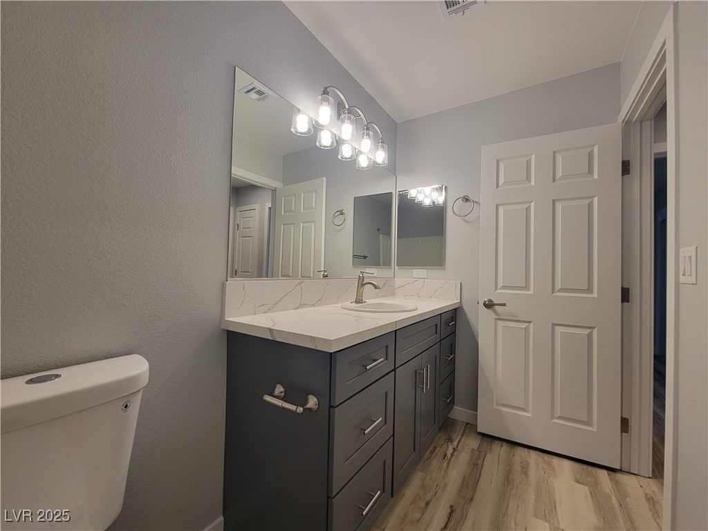 1021 East Manse Road Pahrump, NV 89048 - Photo 13 of 25 Bathroom with vanity, light wood-style floors, and a textured wall