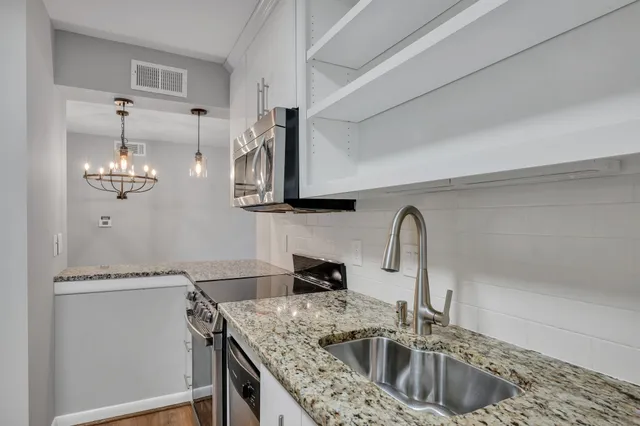 a kitchen with stainless steel appliances granite countertop a sink dishwasher a stove and a refrigerator with wooden floor