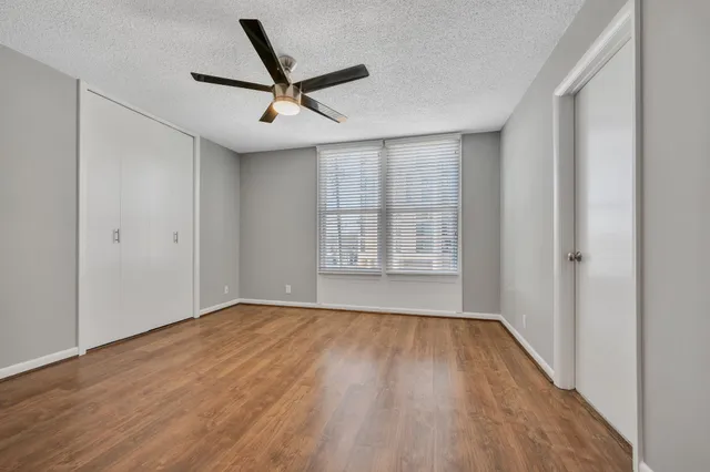 a view of empty room with wooden floor and fan