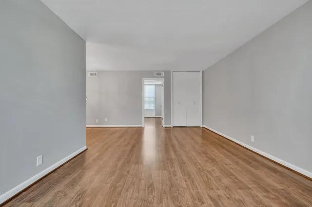 an empty room with wooden floor and windows
