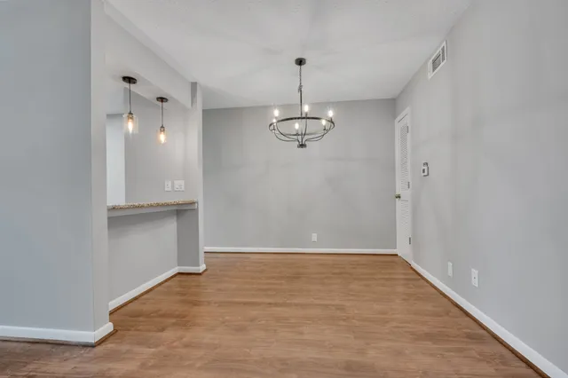 a view of a hallway with wooden floor and chandelier