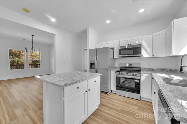 a kitchen with kitchen island granite countertop a stove sink and microwave