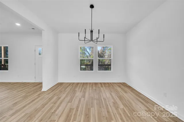 a view of a room with wooden floor chandelier and a window