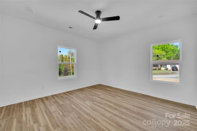 a view of empty room with window and ceiling fan