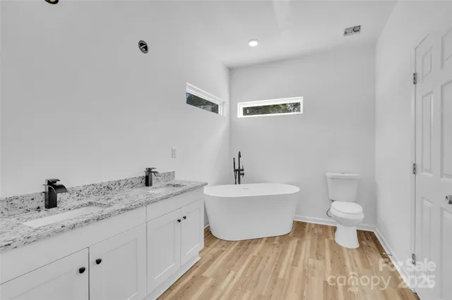 a spacious bathroom with a toilet sink double vanity and mirror