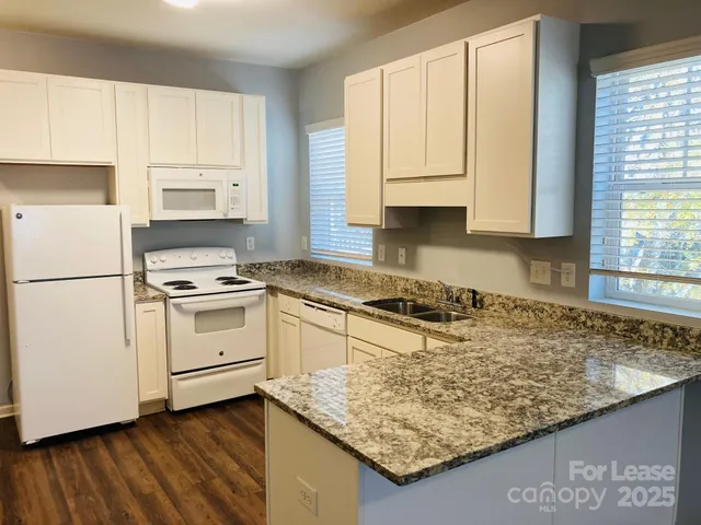 a kitchen with granite countertop white cabinets and white appliances