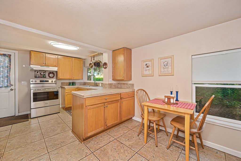 6252 Pony Express Trail Pollock Pines, CA 95726 - Photo 20 of 43 a kitchen with stainless steel appliances granite countertop a stove top oven a sink a dining table and chairs