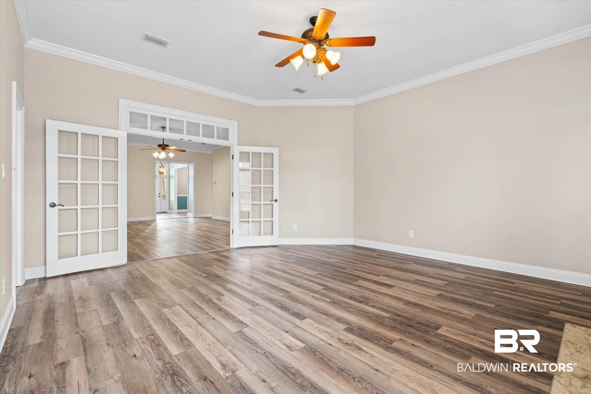 704 Edinburgh Avenue Foley, AL 36535 - Photo 9 of 32 Empty room featuring french doors, a ceiling fan, wood finished floors, and crown molding