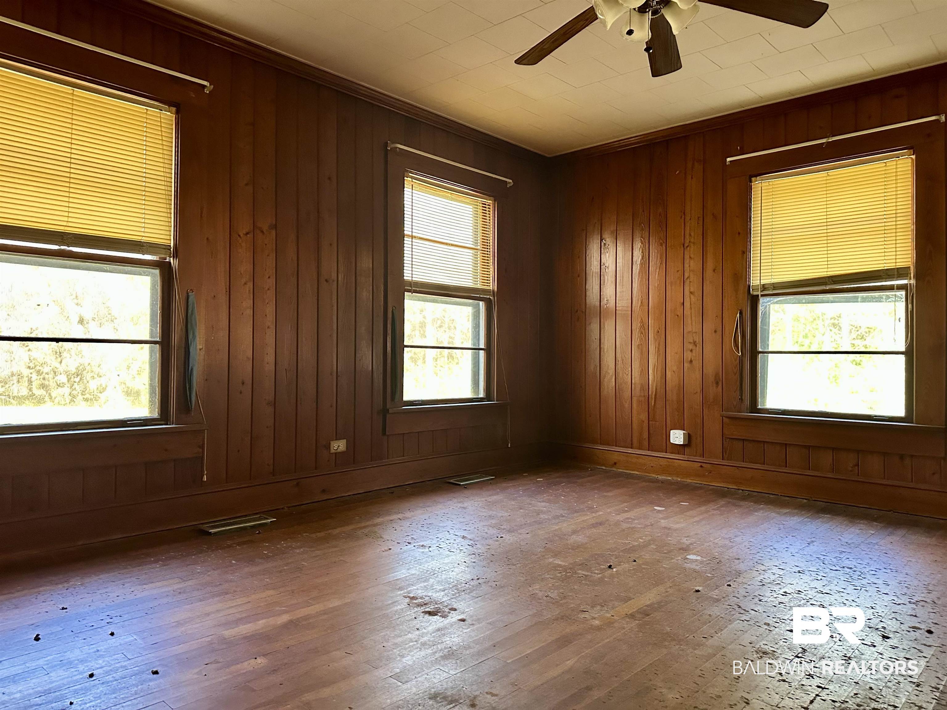 3556 Damascus Road Brewton, AL 36426 - Photo 16 of 17 Spare room featuring hardwood / wood-style floors, wood walls, a wealth of natural light, and ceiling fan