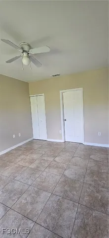an empty room with a ceiling fan and window