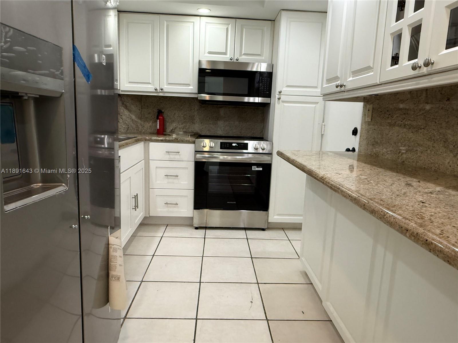 5005 Collins Avenue, Unit 823 Miami Beach, FL 33140 - Photo 14 of 34 a kitchen with granite countertop a stove a sink and a microwave