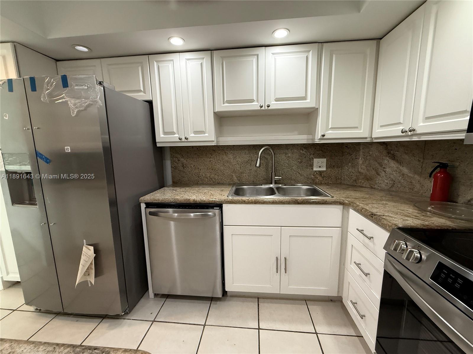 5005 Collins Avenue, Unit 823 Miami Beach, FL 33140 - Photo 15 of 34 a kitchen with stainless steel appliances granite countertop a refrigerator sink and cabinets