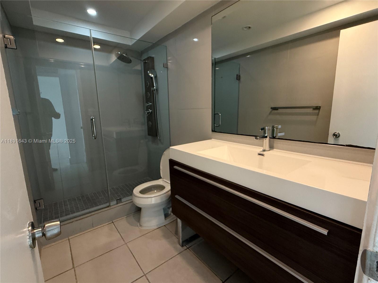 5005 Collins Avenue, Unit 823 Miami Beach, FL 33140 - Photo 27 of 34 a bathroom with a sink a toilet a mirror and shower