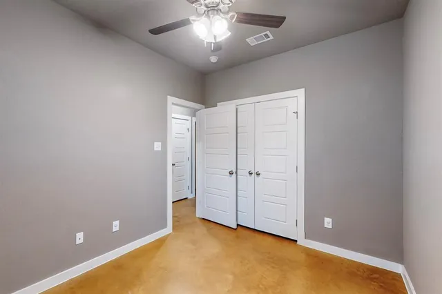 an empty room with chandelier fan and windows